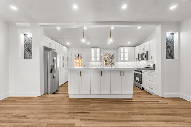 kitchen featuring appliances with stainless steel finishes, pendant lighting, a center island, light hardwood / wood-style floors, and white cabinetry