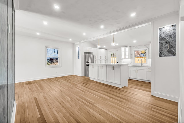 kitchen with stainless steel refrigerator with ice dispenser, decorative light fixtures, light hardwood / wood-style flooring, a center island, and white cabinetry