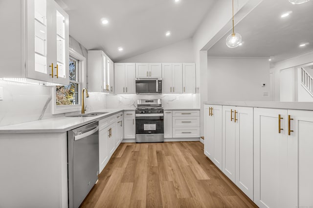 kitchen featuring appliances with stainless steel finishes, vaulted ceiling, white cabinetry, and sink