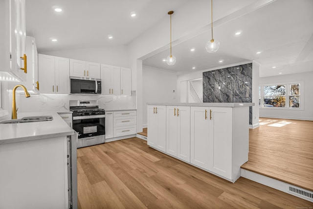 kitchen with hanging light fixtures, white cabinetry, sink, and stainless steel appliances