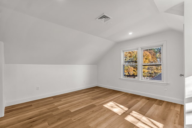 additional living space with light hardwood / wood-style floors and vaulted ceiling