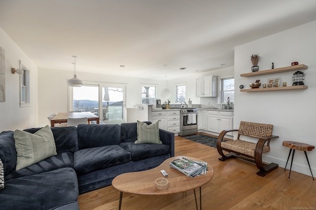 living room with a healthy amount of sunlight, sink, and light hardwood / wood-style flooring