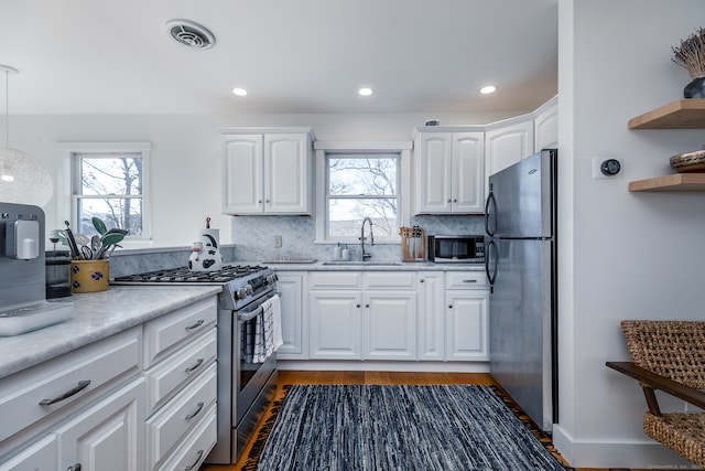 kitchen featuring tasteful backsplash, sink, white cabinets, and appliances with stainless steel finishes