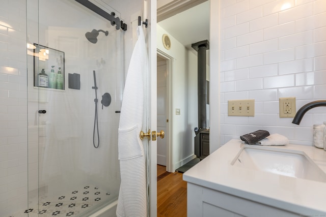 bathroom with tiled shower, hardwood / wood-style floors, vanity, and tile walls