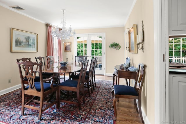 dining room featuring an inviting chandelier, ornamental molding, dark wood-type flooring, and french doors