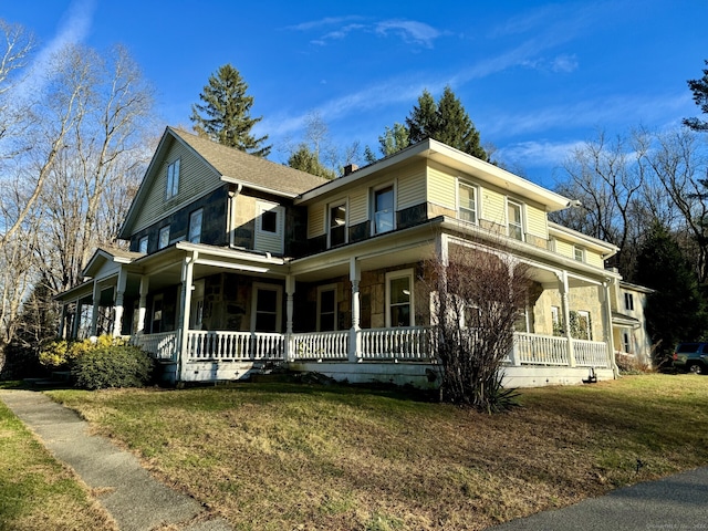 view of front of home featuring stone siding, a porch, and a front lawn