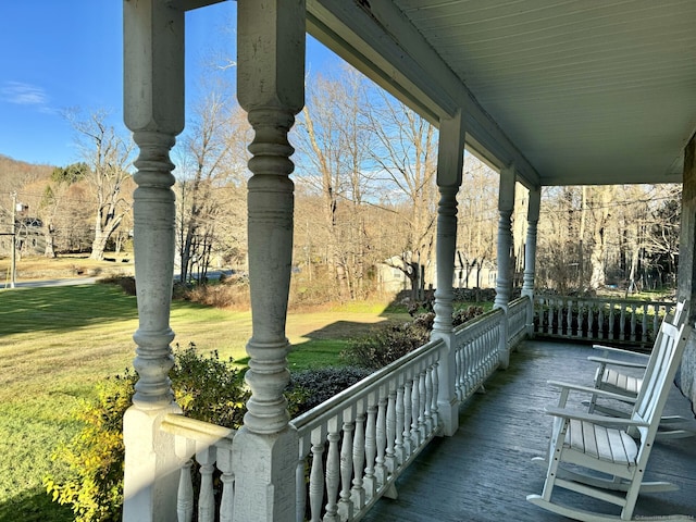 wooden deck featuring a lawn and covered porch