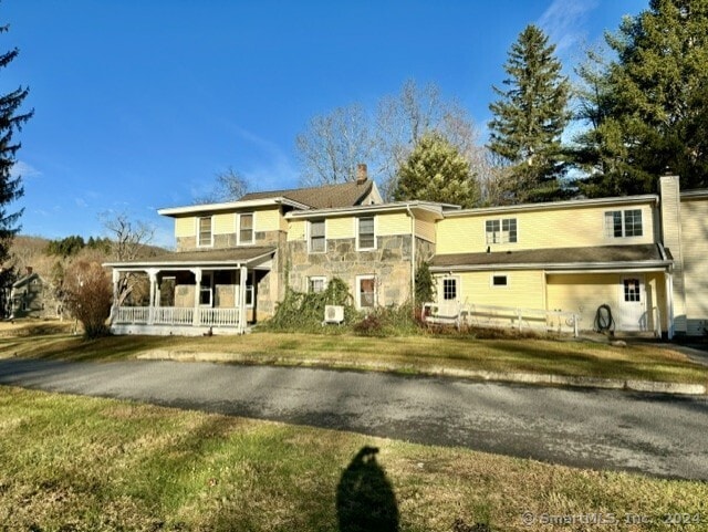 view of front of property with a front yard, covered porch, and a chimney