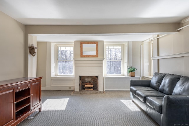 living area featuring a fireplace with flush hearth, a healthy amount of sunlight, radiator, and carpet