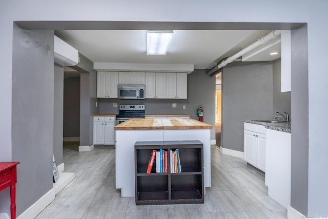 kitchen featuring a sink, light wood-type flooring, appliances with stainless steel finishes, and wooden counters