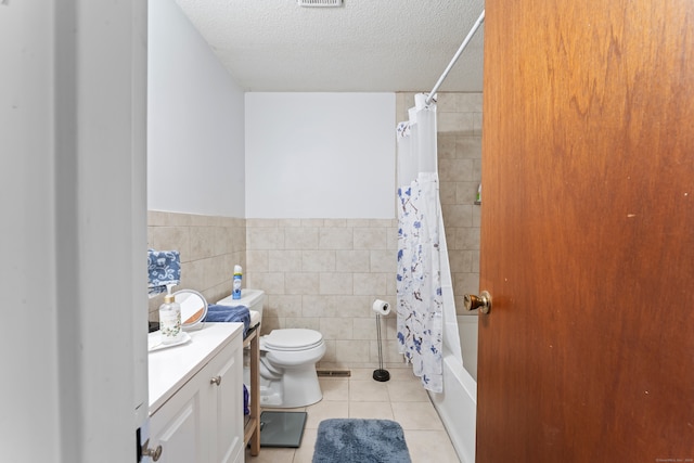 full bathroom with tile patterned floors, a textured ceiling, shower / bath combo with shower curtain, vanity, and tile walls