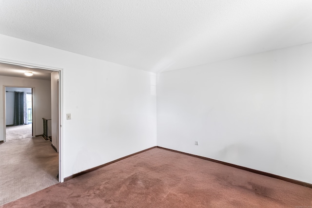 empty room with light colored carpet and a textured ceiling