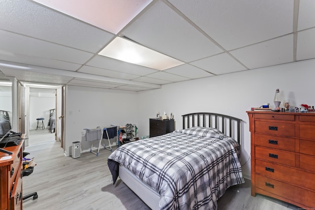 bedroom with light hardwood / wood-style floors and a drop ceiling