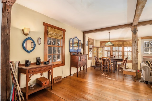 dining space with beam ceiling and hardwood / wood-style floors