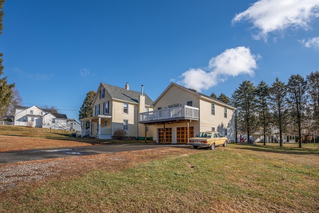 back of house with a garage, a yard, and a deck