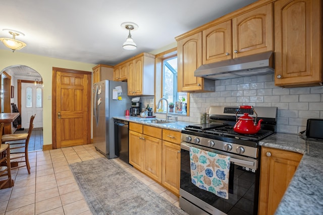 kitchen featuring appliances with stainless steel finishes, tasteful backsplash, light stone counters, sink, and light tile patterned flooring