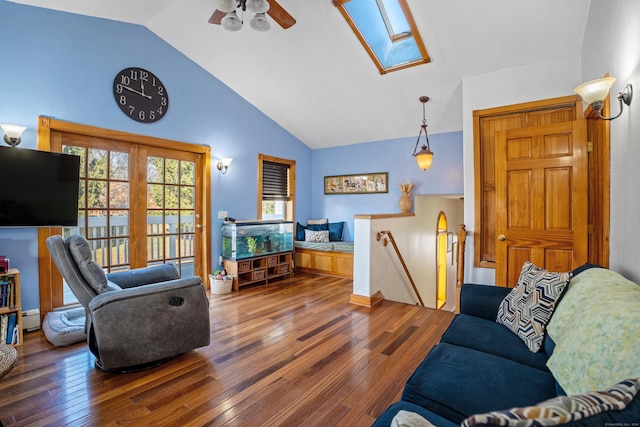 living room featuring hardwood / wood-style floors, high vaulted ceiling, a baseboard heating unit, a skylight, and ceiling fan