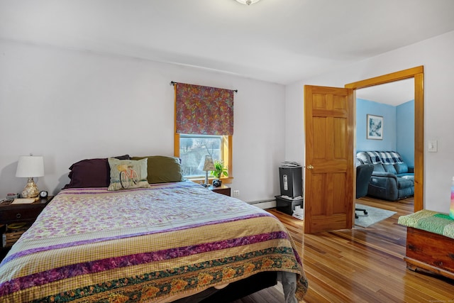 bedroom with hardwood / wood-style flooring and a baseboard heating unit