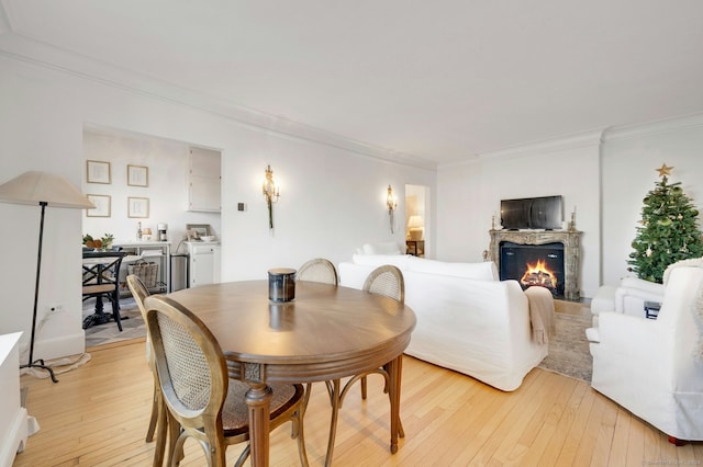 dining room featuring washer / dryer, light hardwood / wood-style flooring, and crown molding