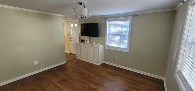 spare room with crown molding, dark wood-type flooring, and an inviting chandelier