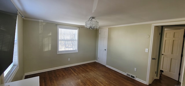 unfurnished room featuring dark hardwood / wood-style flooring, crown molding, and a notable chandelier