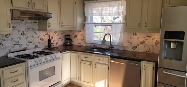 kitchen featuring sink, stainless steel appliances, dark stone counters, and tasteful backsplash