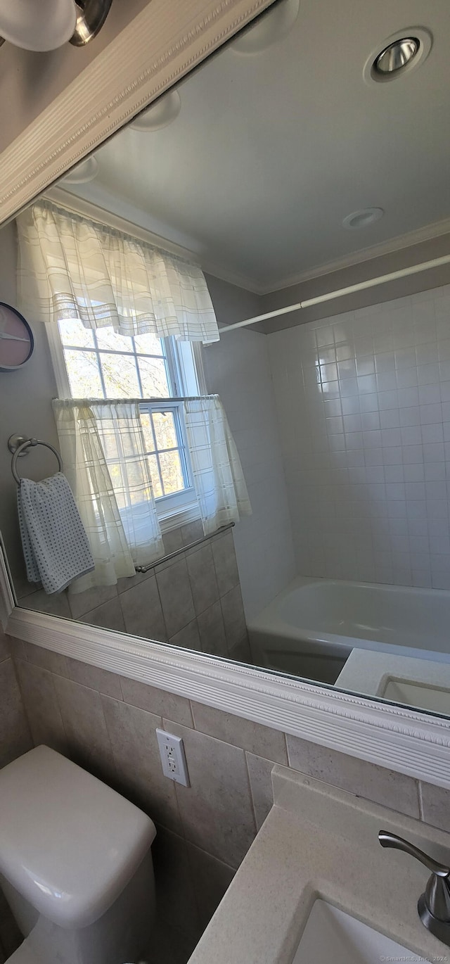 bathroom featuring toilet, tile walls, crown molding, and tiled shower / bath