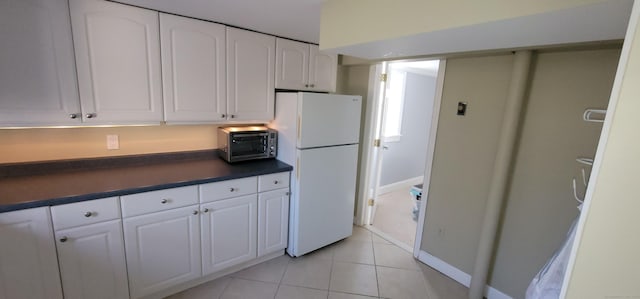 kitchen featuring white cabinets, light tile patterned floors, and white fridge