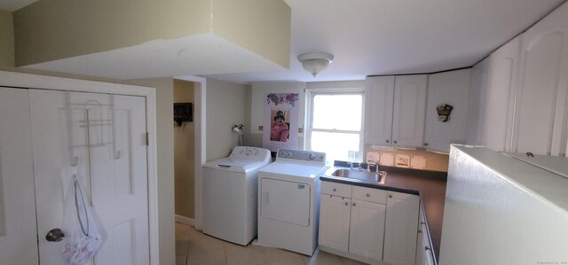 clothes washing area with light tile patterned flooring, cabinets, separate washer and dryer, and sink