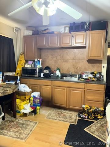 kitchen featuring ceiling fan, sink, and light wood-type flooring