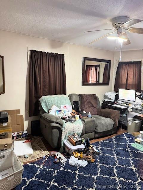 living room with a textured ceiling and ceiling fan