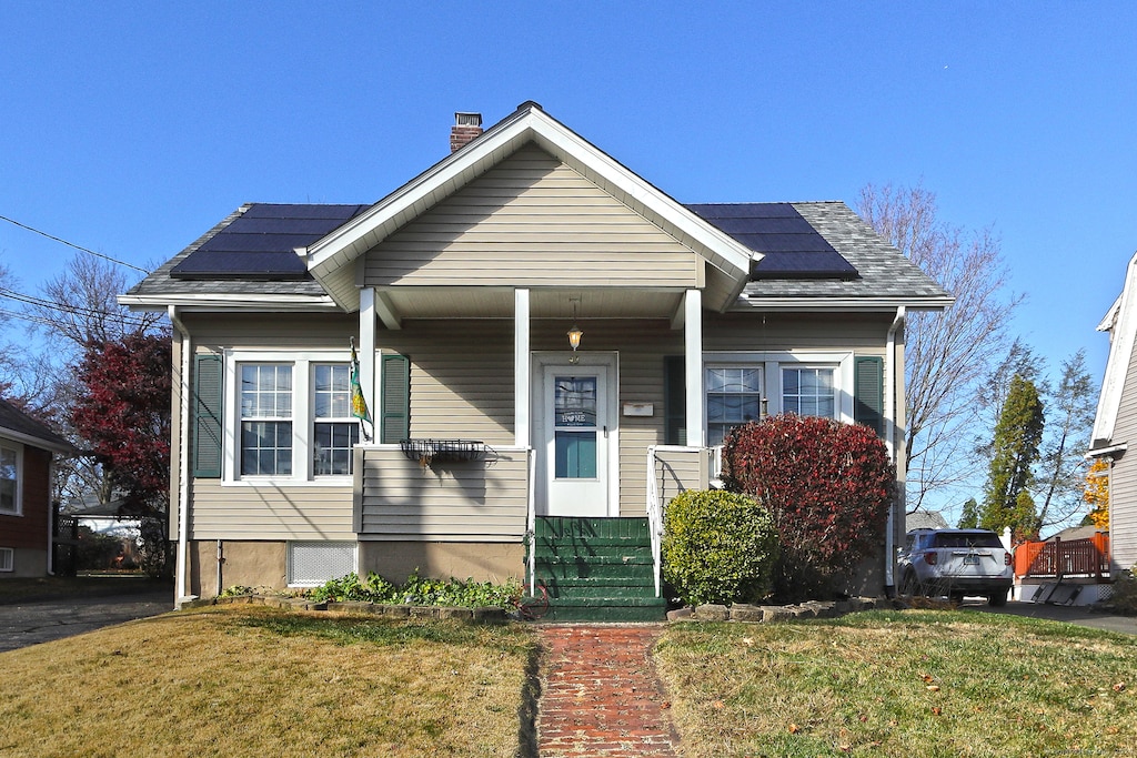 bungalow-style house featuring a front yard and solar panels