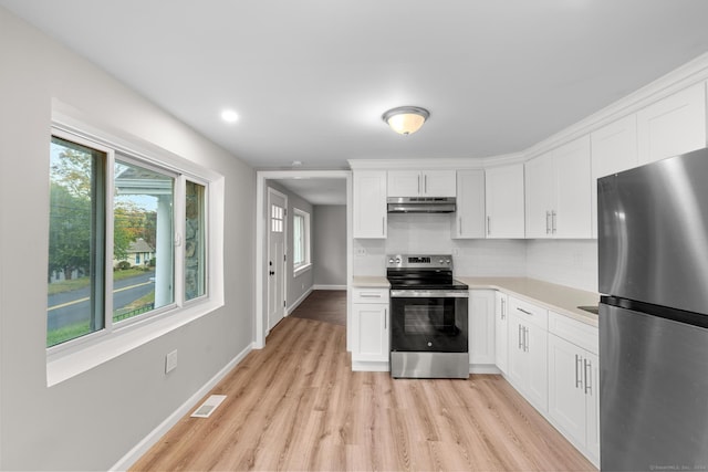 kitchen with tasteful backsplash, light hardwood / wood-style flooring, white cabinets, and stainless steel appliances