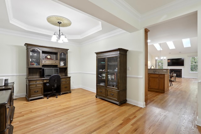 home office with a skylight, sink, light hardwood / wood-style flooring, a notable chandelier, and ornamental molding