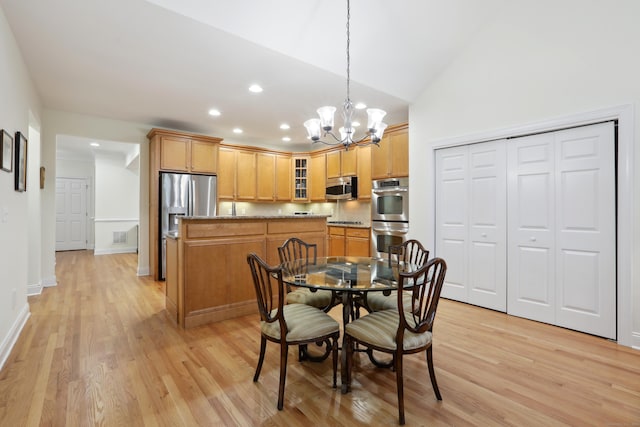 dining area featuring light hardwood / wood-style floors, vaulted ceiling, and a notable chandelier