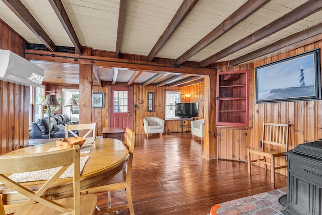 interior space with hardwood / wood-style floors, beam ceiling, a wood stove, and wood walls