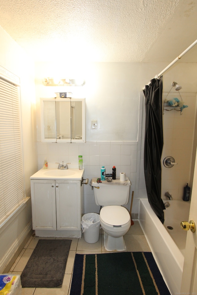 full bathroom featuring vanity, a textured ceiling, shower / bath combo with shower curtain, tile walls, and tile patterned flooring