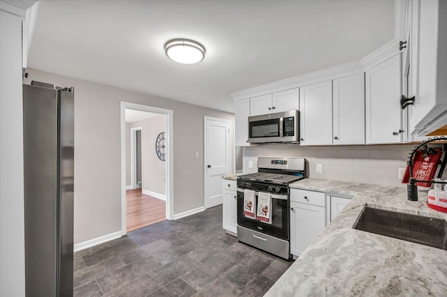 kitchen featuring light stone countertops, sink, decorative backsplash, white cabinets, and appliances with stainless steel finishes