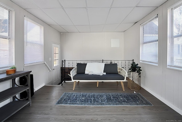 sitting room with a drop ceiling and dark wood-type flooring