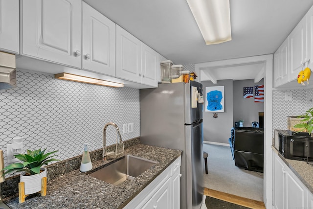 kitchen featuring decorative backsplash, white cabinetry, dark stone countertops, and sink