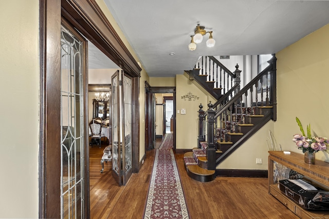 foyer entrance featuring hardwood / wood-style floors, a notable chandelier, and french doors