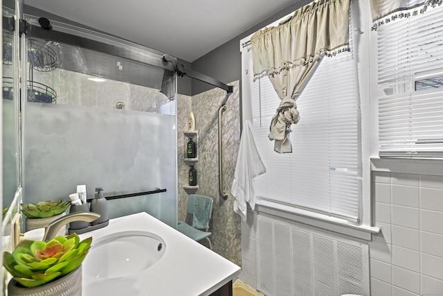 bathroom with a tile shower, vanity, and tile walls