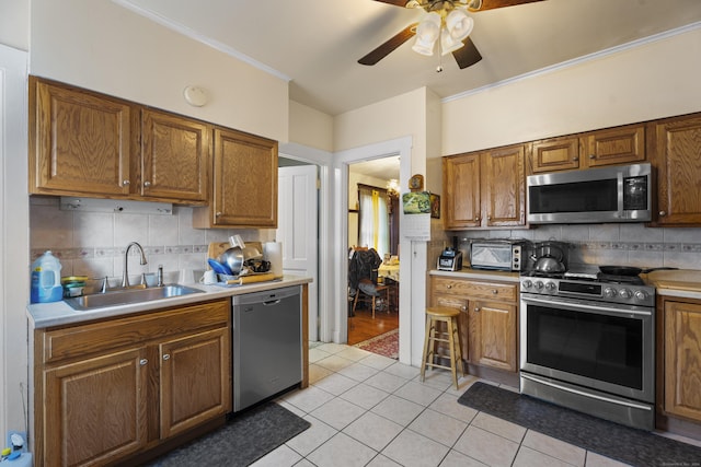 kitchen with backsplash, sink, light tile patterned floors, and stainless steel appliances