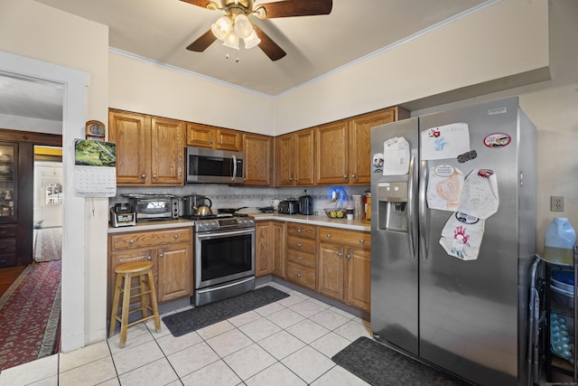 kitchen with ceiling fan, stainless steel appliances, backsplash, light tile patterned floors, and ornamental molding