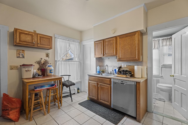 kitchen featuring sink, light tile patterned floors, stainless steel dishwasher, and plenty of natural light