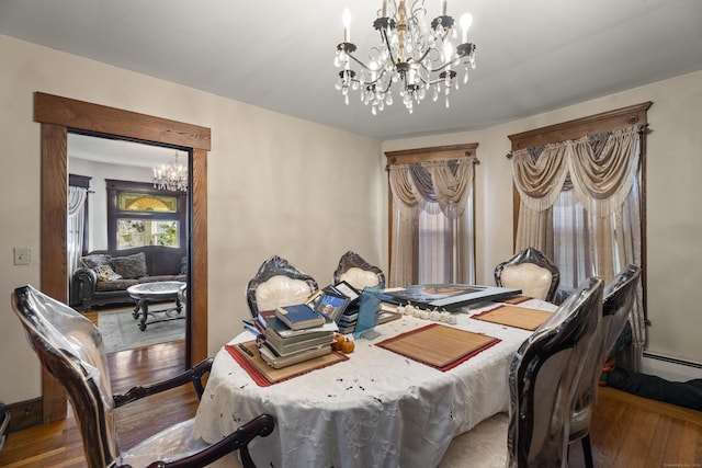 dining space with hardwood / wood-style floors, a baseboard heating unit, and an inviting chandelier