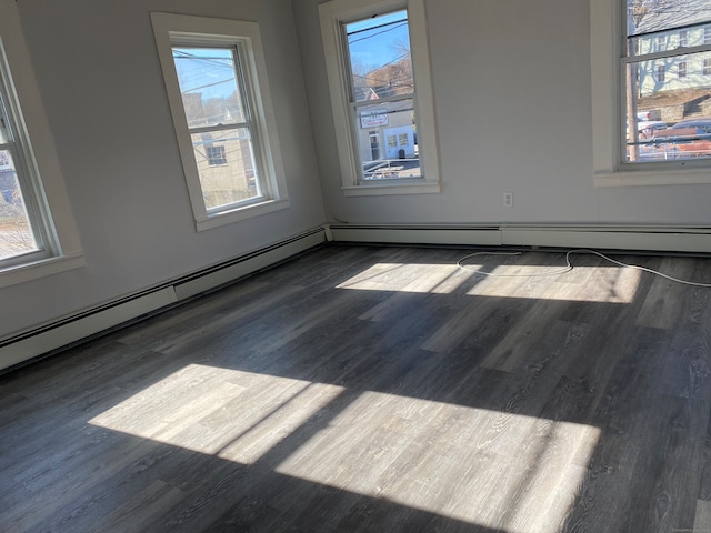 unfurnished room featuring dark wood-type flooring, a healthy amount of sunlight, and a baseboard radiator