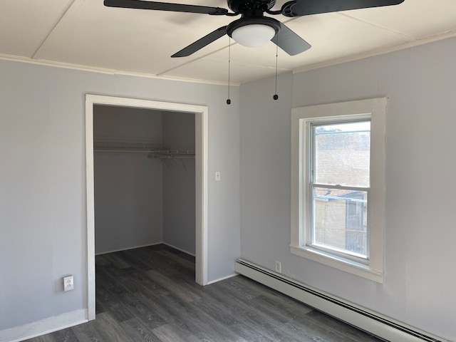 unfurnished bedroom featuring ceiling fan, dark wood-type flooring, crown molding, a baseboard heating unit, and a closet