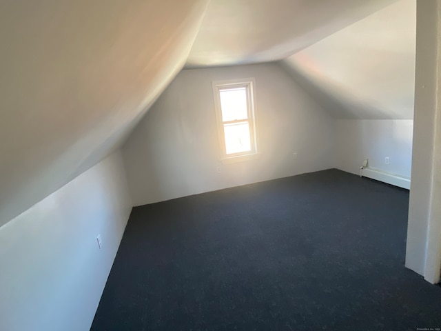 bonus room featuring dark colored carpet, vaulted ceiling, and a baseboard heating unit