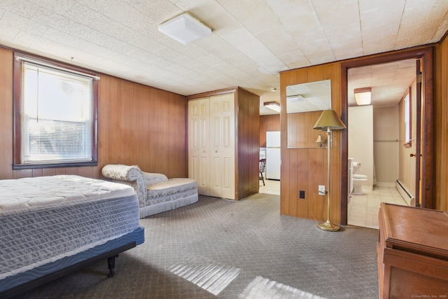 bedroom featuring white refrigerator, baseboard heating, and wooden walls